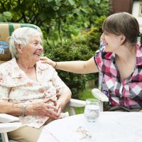 Elderly woman and caregiver sitting outside
