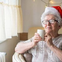 senior-woman-sitting-drinking-coffee-santa-hat