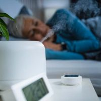 A woman sleeps while using a humidifier in her room after reading up on information about air quality and COPD.