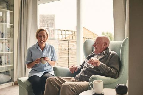 A caregiver shares a laugh and a cup of tea with a senior client as she provides Elbridge home care services.