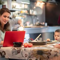 Mothering working and eating at the dining table.