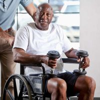 senior man in a wheelchair holding weights