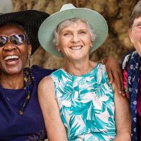 Three senior women laugh as they focus on the positives of getting older.