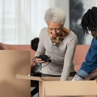 A man knows how important it is to declutter your parents’ home with their help, so he works with his aging mom to pack items into boxes.