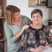 A woman experiencing time-shifting in Alzheimer’s stares ahead as her daughter places a hand on her shoulder.