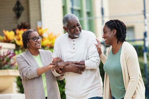 A woman meeting the care needs of both parents joins them for a walk.