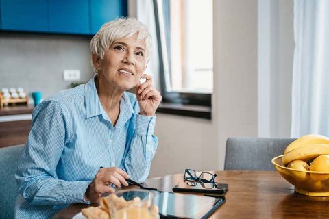 A woman experiencing decision fatigue in dementia caregivers pauses in her work with a confused look on her face.