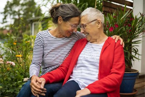 A caregiver practicing nonverbal communication in Alzheimer’s offers a comforting hand to an older woman.