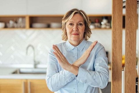 A woman crosses her arms in an X shape in front of her body, indicating that she has learned how to say no as a caregiver.