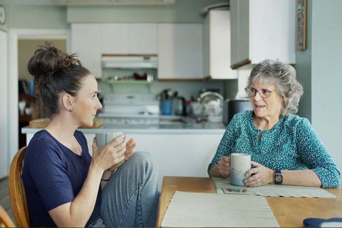 A woman attempts to stay connected in spite of dementia as she sits at the table sharing a cup of coffee with her mom.