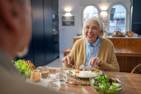 A woman who has overcome loss of appetite in older adults enjoys a healthy meal.