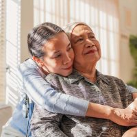 A woman who is learning what to expect as a cancer caregiver hugs her mom.
