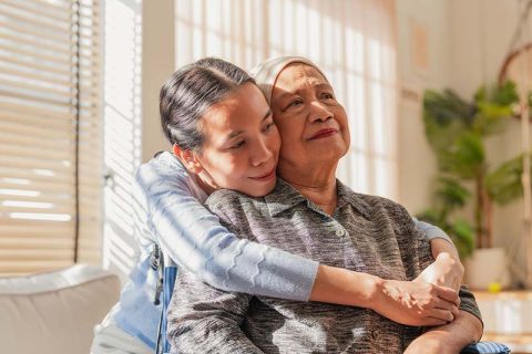 A woman who is learning what to expect as a cancer caregiver hugs her mom.