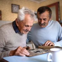 A man is using sports to connect with someone with dementia as they look through old photos together.