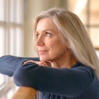A woman is effectively coping with anger in dementia care by pausing to look out the window.