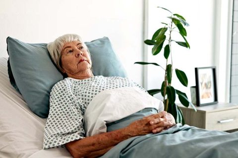 A woman experiencing complications after rehab lies in bed.