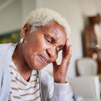 A woman who struggles with morning headaches from COPD closes her eyes and holds her head.