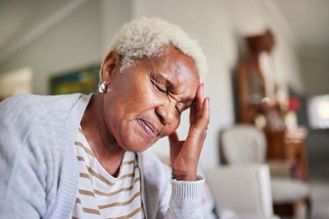A woman who struggles with morning headaches from COPD closes her eyes and holds her head.