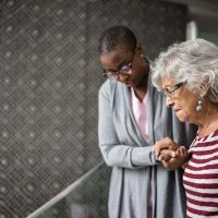 A woman displaying some of the signs of early Alzheimer’s receives a helping hand from her caregiver.