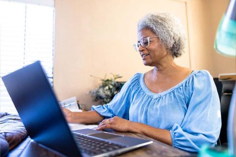 So many older adults are using artificial intelligence, including this woman who smiles as she works on her laptop.