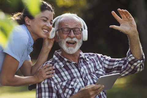 A man who has found relief from dementia-related agitation smiles and enjoys music with his caregiver.