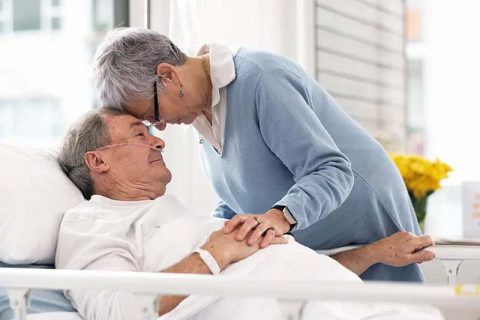 A woman comforts her husband as he experiences dementia-related hospital challenges.