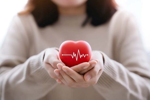 A woman holds a heart, symbolizing the unique differences in heart disease in women.