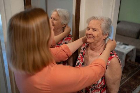 A woman who knows what to look for as senior skin changes checks her mother’s neck and face for new spots.