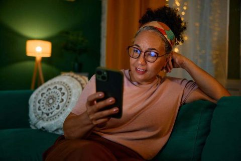 A woman caring for aging parents stares at her phone late at night.