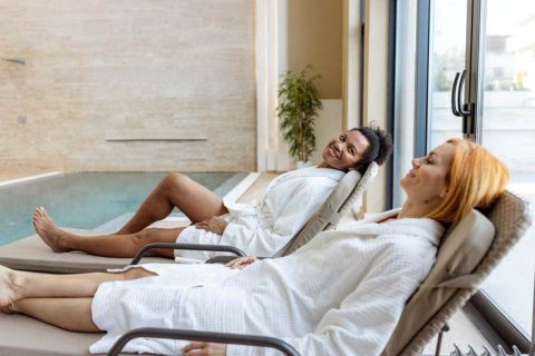 A woman relaxes with her friend to alleviate caregiver stress.
